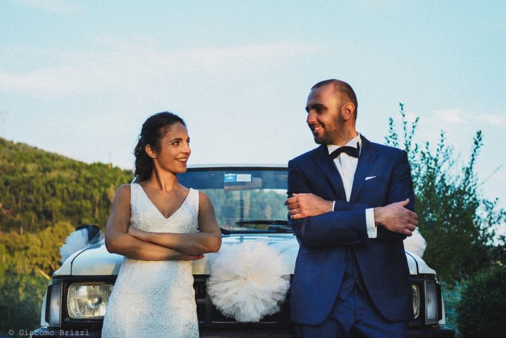 Foto simpatica ai due sposi appoggiati alla loro auto prima di partire, fotografo matrimonio pietrasanta versilia