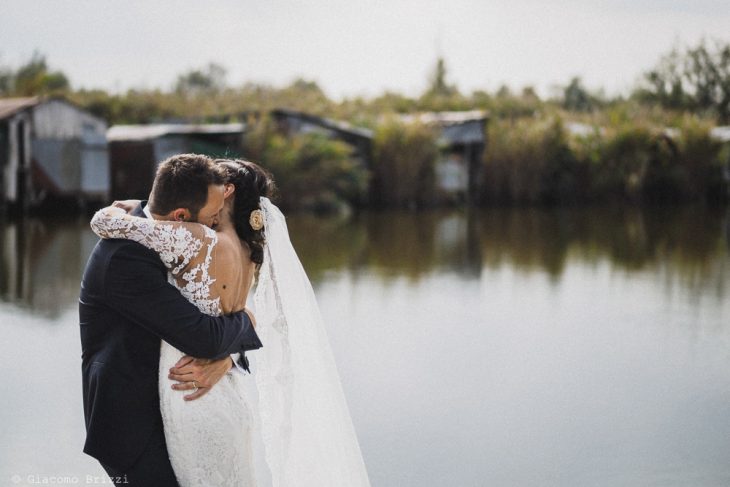 Un appassionato abbraccio degli sposi in riva al laghetto al matrimonio valle di badia